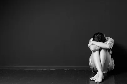 Mulher triste sentada no canto de uma sala, cabeça sobre os joelhos, rosto escondido, preto e brancoIndexador: Rutkovski.byFonte: 116357448<!-- NICAID(14334901) -->