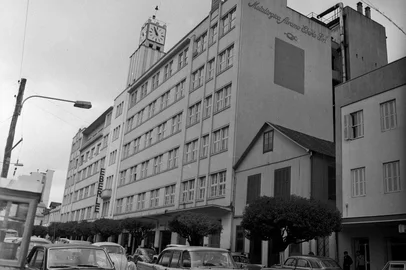 Exposição fotográfica "Caxias do Sul, nossa aldeia! Um recorte do período 65-85", no Sesc. Na foto, Rua Sinimbu, 1971: prédio da Metalúrgica Abramo Eberle, símbolo máximo do desenvolvimento econômico de Caxias até a década de 1970. Curiosidades: contrastando com o moderno Eberle, o lendário casarão de madeira que abrigou a vidraçaria e a residência da família Guidali, em uma Sinimbu ainda de mão dupla.Autoria:  Mauro De Blanco, acervo Arquivo Histórico Municipal João Spadari Adami<!-- NICAID(13220935) -->