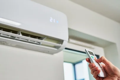 Hand adjusting temperature on air conditionerAr condicionado - Foto: Lazy_Bear/stock.adobe.comFonte: 483935256<!-- NICAID(15968697) -->