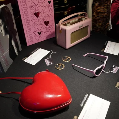 Accessories including earrings, heart-shaped sunglasses and purse are displayed during the New York press and public exhibition  of the "Property From The Life And Career Of Amy Winehouse" by Julien's Auctions in New York, October 11, 2021. - Dozens of dresses, including the famous one Amy Winehouse wore during her dramatic last concert in 2011, books, records, bags and objects that belonged to the British soul diva who died ten years ago will be auctioned in California in November. The US exhibition Tour will be at Hard Rock Cafe New York October 11-17, before the two-day auction event taking place live November 6 and 7. (Photo by TIMOTHY A. CLARY / AFP)<!-- NICAID(14912713) -->