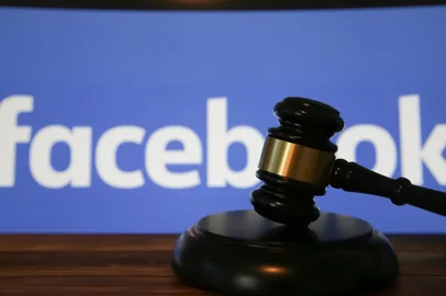 Closeup of isolated judge wood gavel with blurred facebook logo lettering background (focus on hammer head)Fonte: 474402493<!-- NICAID(15499153) -->