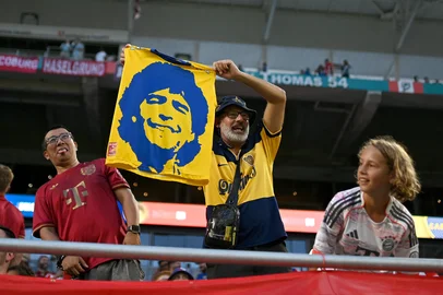 A fan of Boca Juniors holds a flag with the image of late Argentine football legend Diego Maradona before the FIFA Club World Cup 2025 Group C football match between Germany's Bayern Munich and Argentina's Boca Juniors at the Hard Rock stadium in Miami on June 20, 2025. (Photo by Patricia DE MELO MOREIRA / AFP)<!-- NICAID(16064485) -->