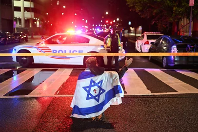 A man draped in the Israeli flag, bearing a cross and the name "Jesus" at its center, gestures as Metropolitan Police officers secure the area outside the Capital Jewish Museum following a shooting that left two people dead in Washington, DC, in the early hours of May 22, 2025. Two Israeli embassy staffers were shot dead late Wednesday, May 21, outside a Jewish museum in Washington by a gunman who shouted "free Palestine," authorities said, with US officials and Israeli diplomats expressing shock and outrage over the killings. (Photo by Alex WROBLEWSKI / AFP)<!-- NICAID(16043030) -->