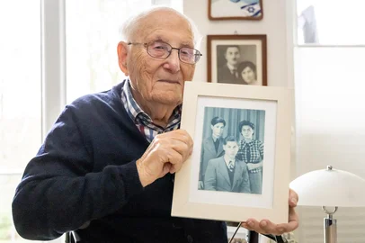 (ARQUIVOS) Albrecht Weinberg, sobrevivente do Holocausto, de 99 anos, posa com uma foto dele (da esquerda para a direita), de seu irmão Dieter e de sua irmã Friedel em sua casa em Leer (Frísia Oriental), Alemanha, em 30 de dezembro de 2024. Em protesto contra a primeira moção aprovada pelos votos da AfD no Bundestag, o sobrevivente do Holocausto Albrecht Weinberg quer devolver a sua Cruz de Mérito Federal. Weinberg disse à agência de notícias AFP em Berlim, em 30 de janeiro de 2025, que temia que a história se repetisse. Weinberg sobreviveu aos campos de concentração de Auschwitz, Dora-Mittelbau e Bergen-Belsen, emigrou para os EUA e regressou à sua terra natal, a Frísia Oriental, depois de décadas como lojista em Nova Iorque. A votação de 29 de janeiro viu a oposição CDU e os seus parceiros da CSU confiarem nos votos da AfD para aprovar uma resolução que apelava a que as fronteiras da Alemanha fossem permanentemente policiadas e a rejeitar todos os migrantes ilegais na sequência de uma série de ataques mortais atribuídos aos migrantes e ao asilo. buscadores. (Foto de FOCKE STRANGMANN/AFP)<!-- NICAID(15965357) -->