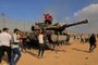 Palestinians take control of an Israeli tank after crossing the border fence with Israel from Khan Yunis in the southern Gaza Strip on October 7, 2023. Barrages of rockets were fired at Israel from the Gaza Strip at dawn as militants from the blockaded Palestinian enclave infiltrated Israel, with at least one person killed, the army and medics said. (Photo by SAID KHATIB / AFP)<!-- NICAID(15562970) -->