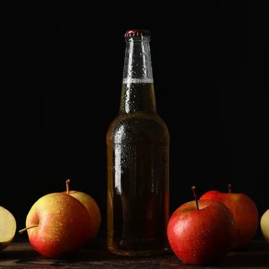 Composition with cider and apples on wooden table against black backgroundFonte: 349798466<!-- NICAID(16143348) -->