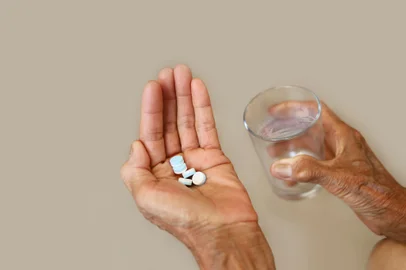 Many pills in a seniorâs hands with glass of water. Painful old age. Caring for the health of the elderlyFonte: 422693251<!-- NICAID(15481697) -->