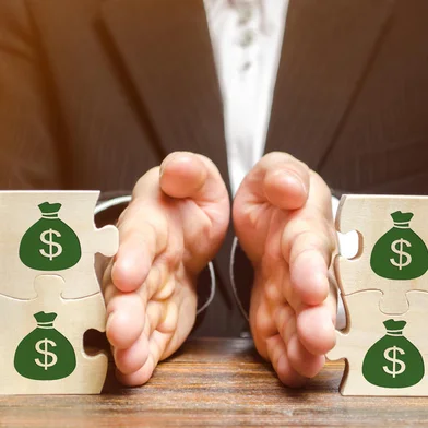 Businessman separates the wooden puzzle with a picture of money. The concept of financial management and distribution of funds. Saving and investing. Property division. Divorce and legal servicesQuebra-cabeça - Finanças. Foto: Andrii Yalanskyi  / stock.adobe.comFonte: 259737465<!-- NICAID(15434250) -->