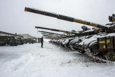 An Ukrainian Military Forces serviceman stands in front of tanks of the 92nd separate mechanized brigade of Ukrainian Armed Forces, parked in their base near Klugino-Bashkirivka village, in the Kharkiv region on January 31, 2022. - The tanks have to restore their combat capability after completing a combat mission in war-torn eastern Ukraine. (Photo by Sergey BOBOK / AFP)<!-- NICAID(15003713) -->