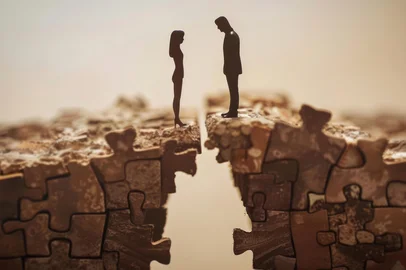 Cracked puzzle pieces symbolize challenges and emotional disconnection in a relationship breakupSilhouettes of two people facing each other over a broken puzzle piece bridge symbolizing a relationship breakup.Fonte: 900492093<!-- NICAID(16239526) -->