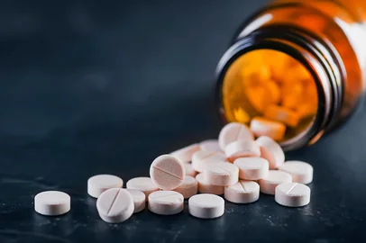 White medical pills or tablets with bottle on black background. Macro side view with copy space.<!-- NICAID(16181067) -->