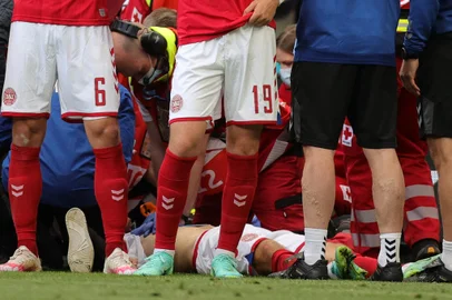 Denmark's players gather as paramedics attend to midfielder Christian Eriksen (not seen) during the UEFA EURO 2020 Group B football match between Denmark and Finland at the Parken Stadium in Copenhagen on June 12, 2021. (Photo by Friedemann Vogel / POOL / AFP)<!-- NICAID(14807660) -->