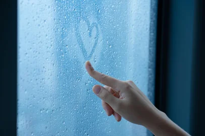 Female hand drawings a heart on a foggy window during the rain. Glass in drops of water. The concept of romance.Female hand drawings a heart on a foggy window during the rain. Glass in drops of water. The concept of romanceIndexador: kukota ekaterinaFonte: 378856606<!-- NICAID(15134752) -->