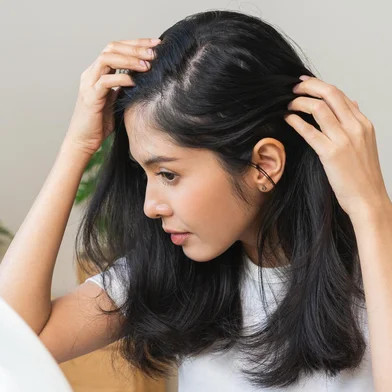 Damaged hair symptom, problem hair fall asian young woman, girl worry about balding, looking at scalp in mirror, hand in break into front hair loss, thin problem. Health care treatment for beauty.Fonte: 634401910<!-- NICAID(15802599) -->