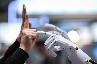 A man interacts with PIB (Printable Intelligent Bot), a 3D printable humanoid robot, at the booth of German Federal Ministry of Education and Research during the opening of the Hannover Messe industrial trade fair for mechanical and electrical engineering and digital industries, on March 31, 2025 in Hanover, northern Germany. The fair opens its doors to the public on March 31 and will be running until April 4, 2025. According to the Hannover Messe, "more than 4,000 companies will be acting as an interconnected industrial ecosystem and demonstrating how climate neutrality can be achieved through electrification, digitization and automation". (Photo by RONNY HARTMANN / AFP)Editoria: FINLocal: HanoverIndexador: RONNY HARTMANNSecao: industrial productionFonte: AFPFotógrafo: STR<!-- NICAID(16008351) -->