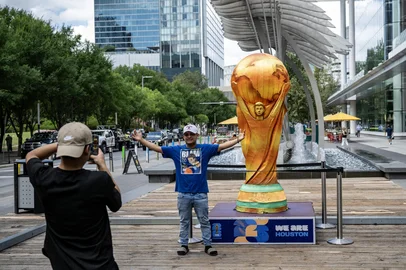 A man poses for a picture next to a replica of the World Cup trophy in downtown Houston, Texas, on June 10, 2026, ahead of the 2026 FIFA World Cup. (Photo by RONALDO SCHEMIDT / AFP)<!-- NICAID(16304692) -->