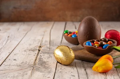 Colorful chocolate Easter eggs on wooden tableFonte: 484873125<!-- NICAID(15997213) -->
