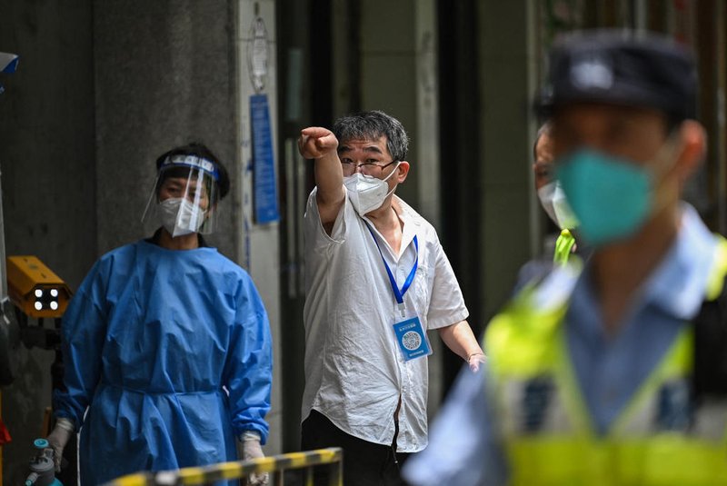 A man reacts as a resident speaks with a person at the entrance of a neighbourhood under a Covid-19 lockdown in the Jing'an district of Shanghai on June 2, 2022. (Photo by Hector RETAMAL / AFP)<!-- NICAID(15113188) -->