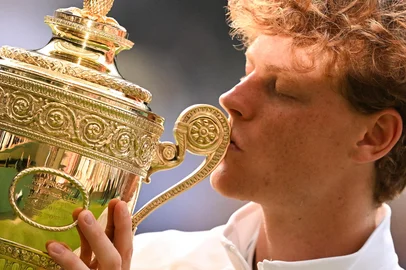 Italy's Jannik Sinner kisses the winner's trophy as he poses for pictures following his victory against Spain's Carlos Alcaraz at the end of their men's singles final tennis match on the fourteenth day of the 2025 Wimbledon Championships at The All England Lawn Tennis and Croquet Club in Wimbledon, southwest London, on July 13, 2025. (Photo by Kirill KUDRYAVTSEV / AFP) / RESTRICTED TO EDITORIAL USE<!-- NICAID(16079443) -->