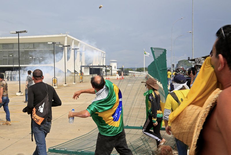 Supporters of Brazilian former President Jair Bolsonaro clash with riot police at Planalto Presidential Palace in Brasilia on January 8, 2023. - Hundreds of supporters of Brazil's far-right ex-president Jair Bolsonaro broke through police barricades and stormed into Congress, the presidential palace and the Supreme Court Sunday, in a dramatic protest against President Luiz Inacio Lula da Silva's inauguration last week. (Photo by Sergio Lima / AFP)Editoria: WARLocal: BrasíliaIndexador: SERGIO LIMASecao: demonstrationFonte: AFPFotógrafo: STR<!-- NICAID(15315545) -->