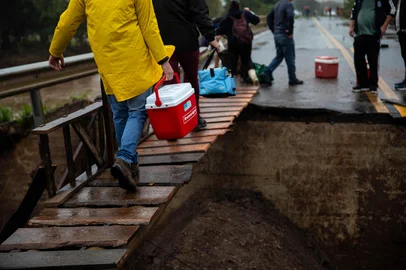 CANDELÁRIA, RS, BRASIL, 03.05.2024: Moradores constroem ponte improvisada em rodovia estadual para religar Candelária a municípios vizinhos. Doze passos costumam ser facilmente percorridos cotidianamente. Porém, para moradores de Candelária, essa breve caminhada ganhou um novo significado após a recuperação de forma improvisada de uma pequena parte da rodovia sobre o Rio Pardo, no quilômetro 137 da RS-287. O ponto foi severamente comprometido com a enchente, interrompendo a principal ligação entre Candelária a Vera Cruz e Santa Cruz do Sul. Foto: Camila Hermes/Agencia RBS<!-- NICAID(15753961) -->