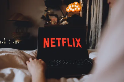 Netflix logo on the laptop screen. Young woman watching netflixFonte: 388280980<!-- NICAID(15235021) -->