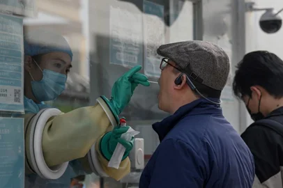 (FILES) This file photo taken on October 25, 2021 shows a health worker taking a swab sample from a man to test for the Covid-19 coronavirus at a nucleic acid collection station in Beijing. - China's leaders have enjoyed public support for their rigid coronavirus measures, but some debate and grumbling has started to emerge over the zero-Covid approach -- unlike other nations that have started to live with the virus. (Photo by Noel Celis / AFP) / TO GO WITH Health-virus-China-policy,FOCUS by Beiyi SEOW<!-- NICAID(14942884) -->
