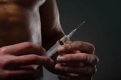 Muscular man with a syringe in his hand. User of anabolic steroids for strength training.<!-- NICAID(16293361) -->