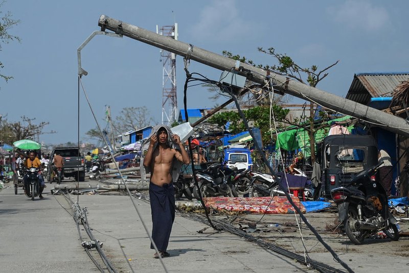 A man walks past destroyed powerlines in Sittwe on May 17, 2023, in the aftermath of Cyclone Mocha's landfall. The death toll in cyclone-hit Myanmar rose to at least 81, according to local leaders, officials and state media, as villagers tried to piece together ruined homes and waited for aid and support. (Photo by SAI Aung MAIN / AFP)<!-- NICAID(15432859) -->