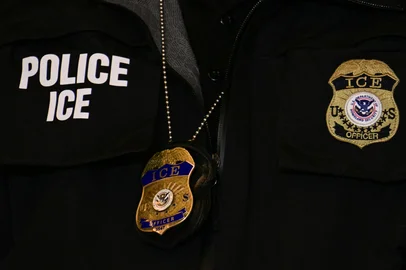 JIM WATSON / POOL An ICE patch and badge are seen on a Department of Homeland Security agent while US Vice President JD Vance speaks at Royalston Square in Minneapolis, Minnesota, on January 22, 2026. The Pentagon has ordered 1,500 US soldiers to prepare for a possible deployment to Minnesota, a state roiled by unrest over an immigration crackdown, US media reported on January 18, 2026. The reported preparations come days after President Donald Trump threatened to invoke the Insurrection Act, which enables use of the military to suppress "armed rebellion" or "domestic violence" -- although a day later he said there was no immediate need for it, following the January 7 killing of Renee Nicole Good by a federal immigration agent. (Photo by Jim WATSON / POOL / AFP)<!-- NICAID(16209880) -->