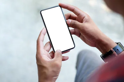 ADOBE STOCK / ADOBE STOCK Close up view of businessman holding mock up smart phone with blank screen. Fonte: 478433379<!-- NICAID(15878062) -->
