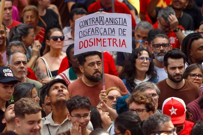 A demonstrator shows a sign that reads "Against amnesty disguised as dosimetry" during a protest against the Brazilian Congress to reject a bill that would modify penalties for crimes against democracy, hence reducing the sentence of former President Jair Bolsonaro, in Sao Paulo, Brazil on December 14, 2025. (Photo by Miguel SCHINCARIOL / AFP)Editoria: POLLocal: Sao PauloIndexador: MIGUEL SCHINCARIOLSecao: demonstrationFonte: AFPFotógrafo: STR<!-- NICAID(16186494) -->