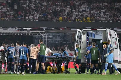 Nacional's defender Juan Manuel Izquierdo (covered) receives medical attention after fainting during the Copa Libertadores round of 16 second leg football match between Brazil's Sao Paulo and Uruguay's Nacional at the MorumBIS stadium in Sao Paulo, Brazil, on August 22, 2024. (Photo by NELSON ALMEIDA / AFP)<!-- NICAID(15847410) -->