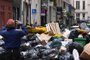 A pedestrian takes a picture of household waste containers in a street of Paris, on March 12, 2023, which have been piling up since collectors went on strike against the French government's proposed pensions reform on March 6, 2023. (Photo by Stefano RELLANDINI / AFP)<!-- NICAID(15373601) -->