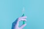 Syringe for injection in hand, latex medical gloves on hand. On a blue background.Seringa, luva, injeção, mão. Foto:  Snejana / stock.adobe.comFonte: 408254657<!-- NICAID(14840403) -->