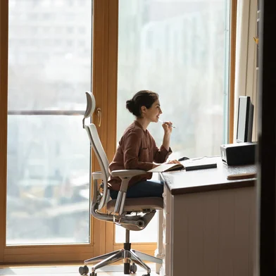 Working at modern home office. Young mixed race female architect interior designer sit at desk on ergonomic chair doing job project on desktop pc. Millennial indian woman study at domestic workplace<!-- NICAID(15859503) -->