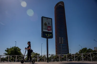A woman rides a scooter past a thermometer that reads 46 degrees Celsius on a street of Seville on July 23, 2024. July 21, 2024 was the hottest day ever registered globally, according to preliminary data published on July 23, 2024 by the EU's climate monitor. The Copernicus Climate Change Service (C3S) said the global average surface air temperature on July 21 was 17.09 degrees Celsius, a fraction above the previous record set in 2023. (Photo by CRISTINA QUICLER / AFP)Editoria: HUMLocal: SevilleIndexador: CRISTINA QUICLERSecao: global changeFonte: AFPFotógrafo: STR<!-- NICAID(15820829) -->