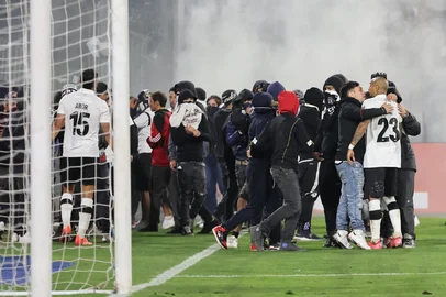 Fans of Colo Colo enter the pitch during the Copa Libertadores group stage football match between Chile's Colo Colo and Brazil's Fortaleza at the Monumental David Arellano stadium in Santiago, on April 10, 2025. Two people were killed Thursday in a stampede as a group of fans tried to force their way into Colo Colo's Monumental stadium in Santiago to watch the match against Brazil's Fortaleza for the Copa Libertadores 2025, authorities said. (Photo by Javier TORRES / AFP)<!-- NICAID(16014854) -->