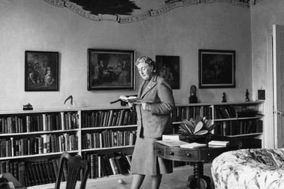 BIO-AGATHA CHRISTIE-LIBRARY-FRESCOESEnglish writer Dame Agatha Christie, reads in March 1946 a book in the library of her home, Greenway House, in Devonshire. The frescoes on the wall, painted by US Navy personnel during their WWII stay (when the house was lent to the US Navy) in Greenway House, depict the exploits of US Navy flotillas. Agatha Christie, born Miller (1890-1976) in Torquay, Devon, wrote, under the surname of her fist husband Colonel Archibald Christie (divorced in 1928) more than 70 detective novels featuring the Belgian detective, Hercule Poirot, or the inquiring village lady, Miss Marple. In 1930, Christie married Max E. L. Mallowan (1904-1978; knighted in 1968), professor of archaeology at London University (1947-78), with whom she travelled on several expeditions. Several of her stories have become popular films, such as "Murder on the Orient Express" (1974) and "Death on the Nile (1978). Christie was made a dame in 1971. (Photo by PLANET NEWS LTD / AFP)Editoria: ACELocal: GREENWAY HOUSESecao: literatureFonte: PLANET NEWS LTD<!-- NICAID(16047477) -->