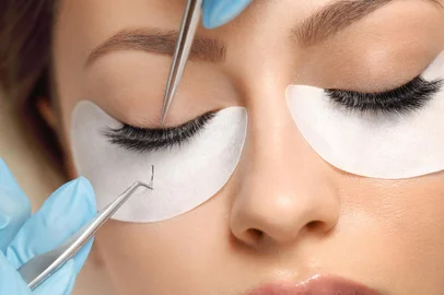 Eyelashes extensions. Fake eyelashes. Eyelash extension procedure.Close up portrait of woman eye with long eyelashes. Professional stylist lengthening female lashes. Master and client in beauty salon.<!-- NICAID(15845914) -->