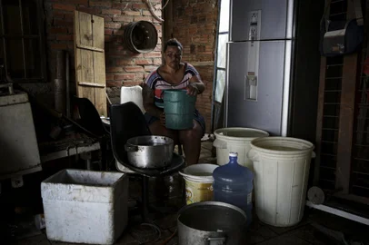 Porto Alegre, RS, Brasil, 15-12-2023: A dona de casa Renata Rosa, 45 anos, com água armazenada em diversos recipientes em casa, no bairro Lomba do Pinheiro. Moradores estão há pelo menos uma semana sem água nas residências e comércios. O desabastecimento de água na região é uma situação que se repete há anos e se agrava com a chegada do verão e as altas temperaturas. Foto: Mateus Bruxel / Agência RBSIndexador: Mateus Bruxel<!-- NICAID(15626901) -->