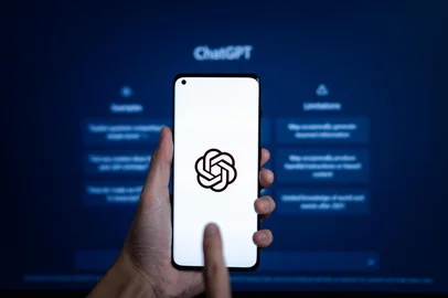 Phayao, Thailand - January 17 2023 : ChatGPT, Hand hold smartphone with AI chatbot by OpenAI open on website on laptop display screen on the background.Fonte: 562115476<!-- NICAID(15337196) -->