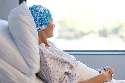 Young woman in bed suffering from cancer. Thoughtful woman battling with tumor looking out of window. Young patient with blue headscarf recovery in hospital on bed. Foto:  Rido/ stock.adobe.comIndexador: francescoridolfi.comFonte: 146219615<!-- NICAID(16089057) -->