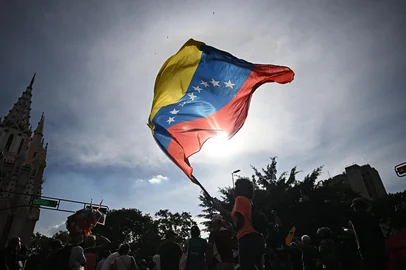 A person flutters a national flag in Caracas on January 3, 2026, after US forces captured Venezuelan leader Nicolas Maduro. President Donald Trump said Saturday that US forces had captured Venezuela's leader Nicolas Maduro after bombing the capital Caracas and other cities in a dramatic climax to a months-long standoff between Trump and his Venezuelan arch-foe. (Photo by Federico PARRA / AFP)<!-- NICAID(16197407) -->