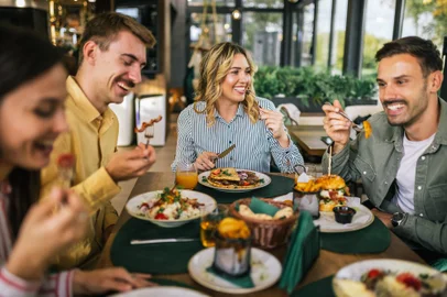 Grupo de amigos felizes almoçando juntos em um restaurante.