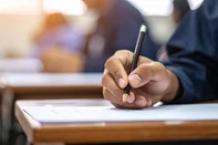 Student hand writing a test in classroom with education concept, selective focus, and blurred background.adobe stockEditoria: BusFonte: 1770069641<!-- NICAID(16234361) -->