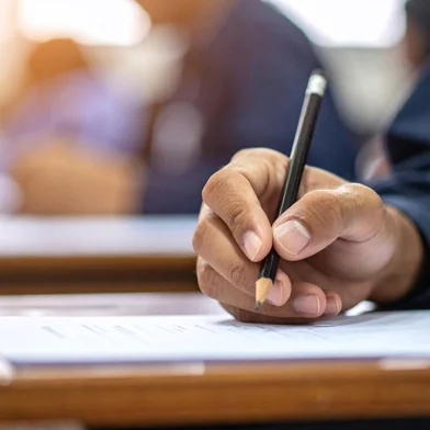 Student hand writing a test in classroom with education concept, selective focus, and blurred background.adobe stockEditoria: BusFonte: 1770069641<!-- NICAID(16234361) -->