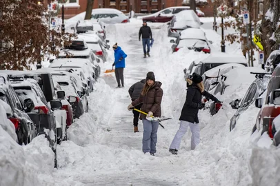 People shovel snow along a residential street in the Charlestown neighborhood in Boston, Massachusetts on January 26, 2026. A monster storm barreling across the United States had killed at least 11 people on Monday, prompting warnings to stay off the roads, mass flight cancelations and power outages after a weekend of misery. The storm dumped snow, sleet and freezing rain across swathes of the country from Texas to New England, with temperatures set to fall dangerously low this week. (Photo by Joseph Prezioso / AFP)<!-- NICAID(16211842) -->