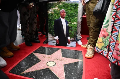 A portrait of US rapper Tupac Shakur is displayed next to his newly unveiled star during his Hollywood Walk of Fame star ceremony in Hollywood, California, on June 7, 2023. Slain rap legend Tupac Shakur was honored with a star on Hollywood's Walk of Fame on Wednesday, almost three decades after the best-selling artist was gunned down in a drive-by shooting. The ceremony paid tribute to a rapper who died at age 25 after a brief but spectacular career, in which he went from backup dancer to self-styled gangsta and one of the most influential figures in hip-hop. (Photo by Robyn Beck / AFP)<!-- NICAID(15451892) -->