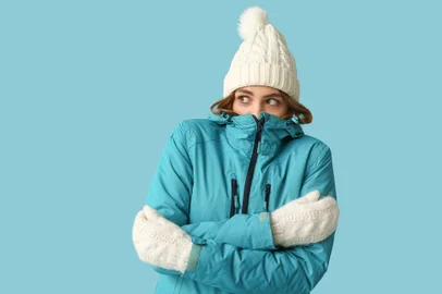 Frozen young woman in warm winter clothes on blue backgroundIndexador: Leonid IastremskyiFonte: 690413846<!-- NICAID(15786606) -->